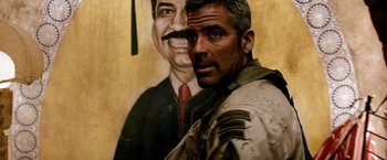 Movie still from “Three Kings” (1999), directed by David O. Russell – A man standing next to a painting of a man; Close Up shot, Over the shoulder angle