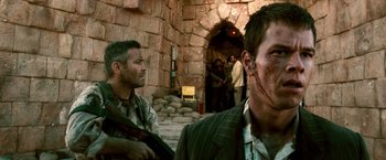 Movie still from “Three Kings” (1999), directed by David O. Russell – Two men in suits and one has a knife in his mouth; Medium shot, Over the shoulder angle