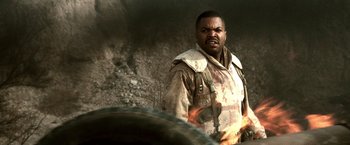 Movie still from “Three Kings” (1999), directed by David O. Russell – A man in a military uniform standing next to a tire; Close Up shot, Low angle