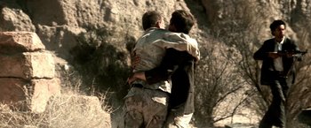 Movie still from “Three Kings” (1999), directed by David O. Russell – Two men hugging each other in the desert; Medium shot, Low angle