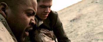 Movie still from “Three Kings” (1999), directed by David O. Russell – Two men in business suits sitting next to each other on the beach; Close Up shot, Over the shoulder angle