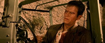 Movie still from “Three Kings” (1999), directed by David O. Russell – A man in a suit driving a vehicle; Close Up shot, High angle