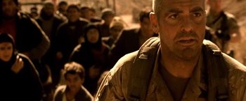 Movie still from “Three Kings” (1999), directed by David O. Russell – A man in a crowd of people with a backpack; Close Up shot, Low angle