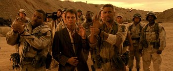 Movie still from “Three Kings” (1999), directed by David O. Russell – A group of men standing next to each other in the desert; Medium shot, Over the shoulder angle