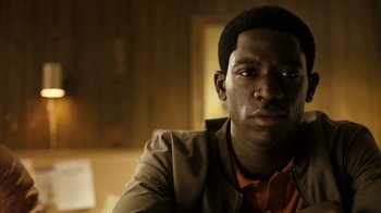 Movie still from “Snowfall” (2017), directed by Hiro Murai – A person sitting in a room; Close Up shot, Low angle