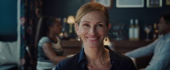 Movie still from “Ticket to Paradise” (2022), directed by Ol Parker – A person smiling at the camera; Close Up shot, Over the shoulder angle