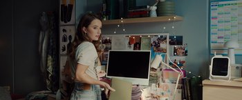 Movie still from “Ticket to Paradise” (2022), directed by Ol Parker – A woman is holding a computer in her hand; Medium shot, Over the shoulder angle