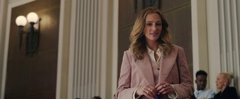 Movie still from “Ticket to Paradise” (2022), directed by Ol Parker – A woman in a pink suit standing in front of a pillar; Medium shot, Over the shoulder angle