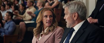 Movie still from “Ticket to Paradise” (2022), directed by Ol Parker – A woman and a man are talking to each other in front of an audience; Medium shot, Over the shoulder angle