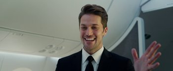 Movie still from “Ticket to Paradise” (2022), directed by Ol Parker – A man wearing a suit and tie smiling for the camera; Close Up shot, Low angle