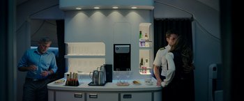 Movie still from “Ticket to Paradise” (2022), directed by Ol Parker – A man standing in front of a counter with drinks on it; Medium shot, Over the shoulder angle