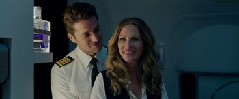 Movie still from “Ticket to Paradise” (2022), directed by Ol Parker – A man standing next to a woman wearing a tie; Close Up shot, Over the shoulder angle