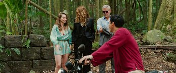 Movie still from “Ticket to Paradise” (2022), directed by Ol Parker – A group of people standing in the woods; Wide shot, Over the shoulder angle