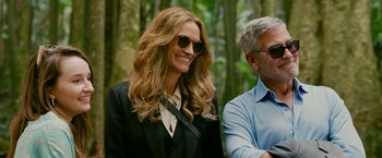 Movie still from “Ticket to Paradise” (2022), directed by Ol Parker – A woman in a suit and sunglasses smiling for the camera; Close Up shot, Over the shoulder angle