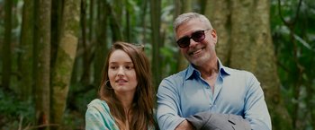 Movie still from “Ticket to Paradise” (2022), directed by Ol Parker – A man and a woman posing for a picture in the woods; Close Up shot, Low angle