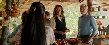 Movie still from “Ticket to Paradise” (2022), directed by Ol Parker – A woman standing in front of a table of food; Medium shot, Over the shoulder angle