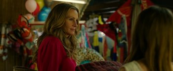 Movie still from “Ticket to Paradise” (2022), directed by Ol Parker – A woman in a red shirt is standing in a room; Medium shot, Over the shoulder angle