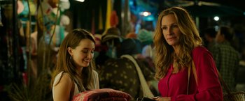 Movie still from “Ticket to Paradise” (2022), directed by Ol Parker – Two women sitting next to each other in a room; Medium shot, Over the shoulder angle