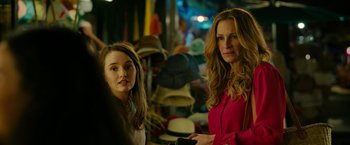 Movie still from “Ticket to Paradise” (2022), directed by Ol Parker – Two women standing next to each other in front of hats; Close Up shot, Over the shoulder angle