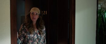 Movie still from “Ticket to Paradise” (2022), directed by Ol Parker – A woman standing in front of a door wearing a head scarf; Close Up shot, Over the shoulder angle