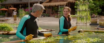 Movie still from “Ticket to Paradise” (2022), directed by Ol Parker – A man and a woman sitting at a table in the water; Medium shot, Over the shoulder angle