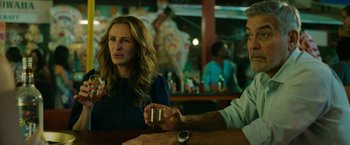 Movie still from “Ticket to Paradise” (2022), directed by Ol Parker – Two people sitting at a table with a glass of wine; Medium shot, Over the shoulder angle