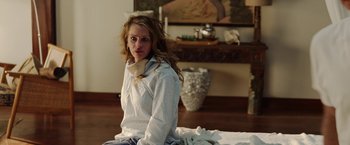 Movie still from “Ticket to Paradise” (2022), directed by Ol Parker – A woman sitting on the ground in a room; Medium shot, Over the shoulder angle