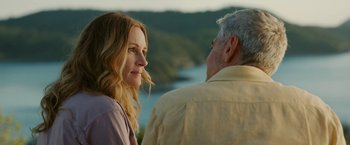 Movie still from “Ticket to Paradise” (2022), directed by Ol Parker – A man and a woman standing next to each other near a body of water; Close Up shot, Over the shoulder angle