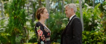 Movie still from “Ticket to Paradise” (2022), directed by Ol Parker – A man and a woman standing next to each other in front of trees; Medium shot, Over the shoulder angle