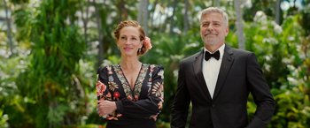 Movie still from “Ticket to Paradise” (2022), directed by Ol Parker – A man and a woman standing next to each other in front of trees; Medium shot, Over the shoulder angle