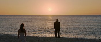 Movie still from “Ticket to Paradise” (2022), directed by Ol Parker – A man standing on the beach looking out at the ocean; Extreme Wide shot, Low angle