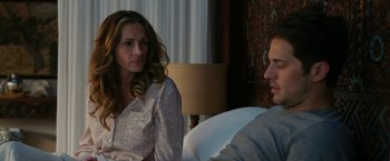 Movie still from “Ticket to Paradise” (2022), directed by Ol Parker – A woman sitting next to a man on a bed; Medium shot, Over the shoulder angle