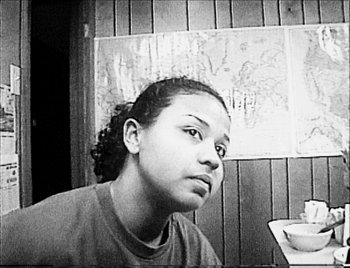 Movie still from “Time” (2020), directed by Garrett Bradley – A black and white photo of a woman sitting at a table; Close Up shot, High angle