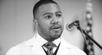 A black and white photo of a man in a white lab coat