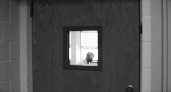 Movie still from “Time” (2020), directed by Garrett Bradley – A person looking out of a window in a room; Medium shot, Over the shoulder angle