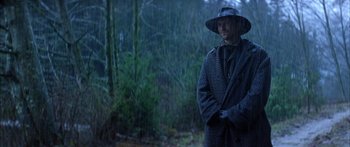 Movie still from “Timecop” (1994), directed by Peter Hyams – A man wearing a hat standing in the rain; Medium shot, Low angle