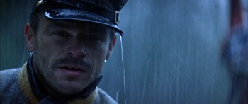 Movie still from “Timecop” (1994), directed by Peter Hyams – A person wearing a hat with rain coming from it; Close Up shot, Low angle