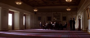 Movie still from “Timecop” (1994), directed by Peter Hyams – A group of people sitting around a table in a room; Extreme Wide shot, Low angle