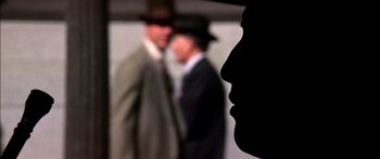 Movie still from “Timecop” (1994), directed by Peter Hyams – Two men in suits and hats standing next to each other; Extreme Close Up shot, Low angle