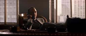 Movie still from “Timecop” (1994), directed by Peter Hyams – A man sitting at a table talking on a phone; Medium shot, Low angle