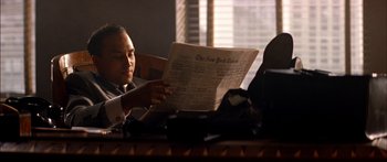 Movie still from “Timecop” (1994), directed by Peter Hyams – A man sitting at a table reading a newspaper; Medium shot, Low angle