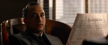 Movie still from “Timecop” (1994), directed by Peter Hyams – A man sitting in a chair reading a newspaper; Close Up shot, Low angle