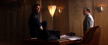 Movie still from “Timecop” (1994), directed by Peter Hyams – A police officer sitting in front of a lamp; Medium shot, Low angle