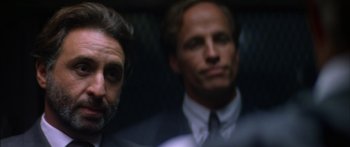 Movie still from “Timecop” (1994), directed by Peter Hyams – A man in a suit and tie next to another man in a suit and tie; Close Up shot, Over the shoulder angle