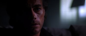 Movie still from “Timecop” (1994), directed by Peter Hyams – A man's face in the dark; Close Up shot, Over the shoulder angle