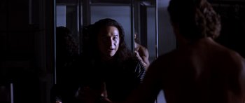 Movie still from “Timecop” (1994), directed by Peter Hyams – A man with long black hair talking to another man in a dark room; Close Up shot, Over the shoulder angle