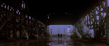 Movie still from “Timecop” (1994), directed by Peter Hyams – Two people walking under an overpass in the rain; Extreme Wide shot, Low angle