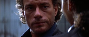 Movie still from “Timecop” (1994), directed by Peter Hyams – A man's face in a black shirt; Close Up shot, Over the shoulder angle