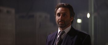 Movie still from “Timecop” (1994), directed by Peter Hyams – A person wearing a suit and tie; Close Up shot, Low angle