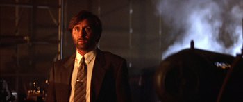 Movie still from “Timecop” (1994), directed by Peter Hyams – A man wearing a suit and tie standing in front of a mirror; Close Up shot, Low angle